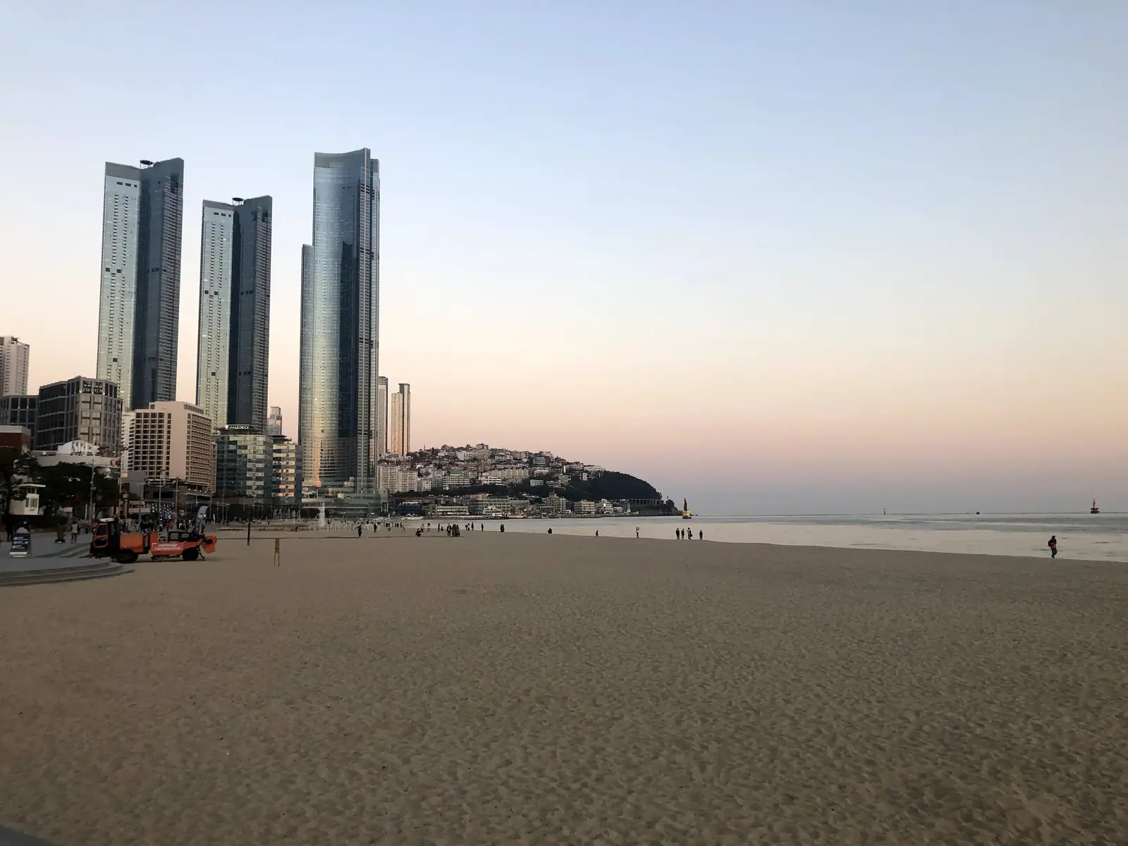 黄昏时分的海云台海滩，身后矗立着 LCT 大楼